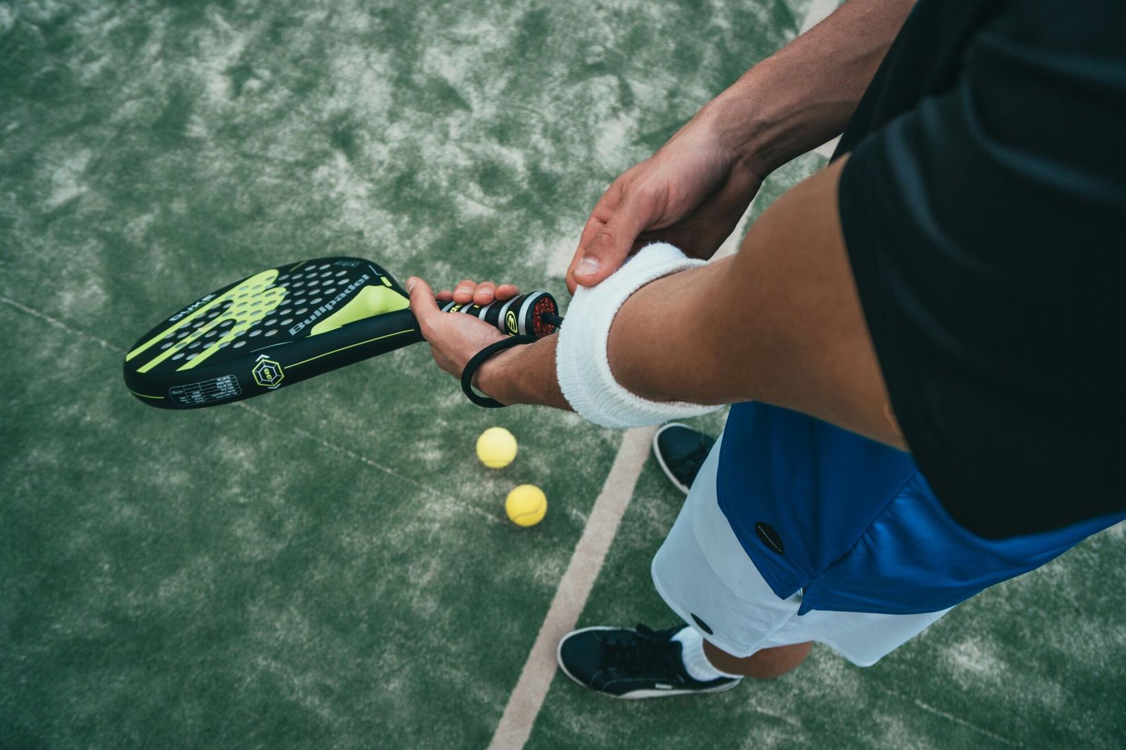 Een padelspeler met racket en ballen op het terrein